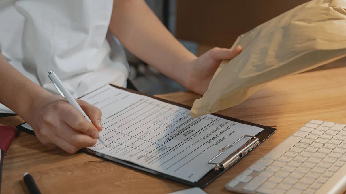 Persona rellenando un documento en una carpeta